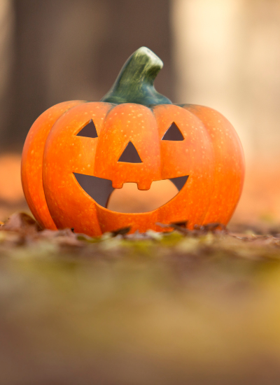 Zucca di Halloween con faccia sorridente nel bosco.