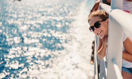 Una ragazza sorride su una barca, guardando il mare scintillante.